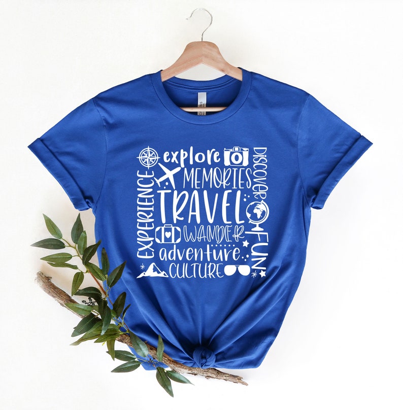 May include: Royal blue t-shirt with a white graphic design that says "Explore, Memories, Travel, Wander, Adventure, Culture, Discover Fun".