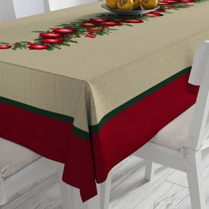 Könnte beinhalten: Ein rechteckiges Tischtuch mit einem beigefarbenen oberen Bereich mit einem Design aus roten Äpfeln und grünen Blättern. Der untere Bereich ist rot mit einem dünnen grünen Streifen. Weiße Stühle umgeben den Tisch.