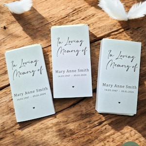 May include: Three white rectangular cards with the text "In Loving Memory of Mary Anne Smith" and the dates "14.03.1947 - 09.01.2024". Each card has a small black heart symbol.