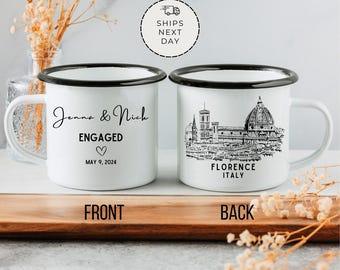 May include: White enamel mug with black text and a black outline. The front of the mug says "Jenna & Nich ENGAGED MAY 9, 2024" with a heart symbol. The back of the mug has a black and white illustration of the Florence skyline with the text "FLORENCE ITALY".