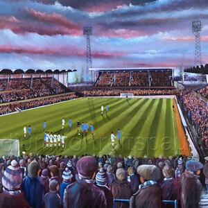 Può includere: Un dipinto di uno stadio di calcio con un campo verde e una folla di persone sugli spalti. Il cielo è di un rosa e un blu vibrante con le nuvole. I giocatori sono al centro del campo, con la porta sullo sfondo.