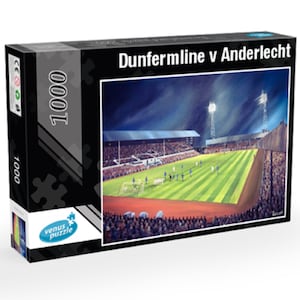 Puede incluir: Un rompecabezas de 1000 piezas que representa un partido de fútbol nocturno entre Dunfermline y Anderlecht. La imagen muestra un estadio con focos y un campo verde con jugadores con uniformes blancos y azules.