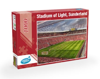 Puede incluir: Un rompecabezas de 1000 piezas que presenta una vista aérea del Stadium of Light, hogar del Sunderland AFC. El estadio está lleno de asientos rojos y un campo verde con jugadores en él. El cielo está nublado y el estadio está rodeado por una estructura de metal.