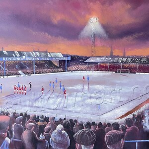 Può includere: Un dipinto di uno stadio di calcio con una folla di persone che guardano una partita. Lo stadio è illuminato da un solo faro e il cielo è di un arancione e un viola vibranti. Le parole "Marstons Renowned Burton Ales Marstons" sono visibili sul lato dello stadio.