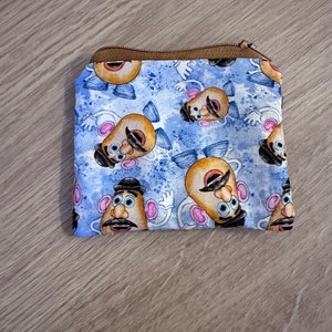 May include: A blue and brown zippered pouch with a repeating pattern of Mr. Potato Head faces.
