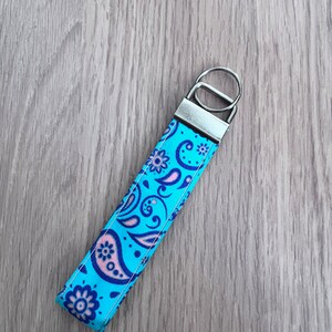 May include: A blue and pink paisley patterned key chain with a silver key ring.