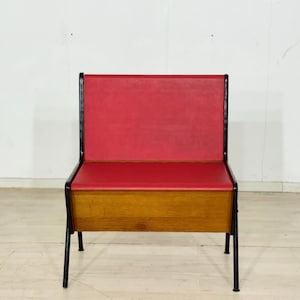 Può includere: Sedia moderna di metà secolo con seduta e schienale rossi. La sedia ha una base in legno e gambe in metallo nero. Il design è semplice e funzionale, con linee pulite e un'estetica minimalista. La sedia è probabilmente realizzata in legno, metallo e vinile.