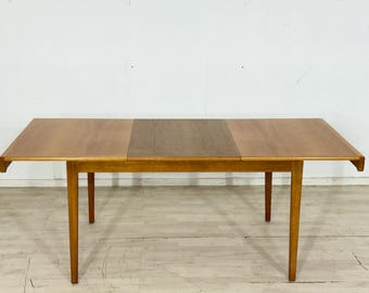Può includere: Un tavolo da pranzo rettangolare in legno con finitura marrone chiaro. Il tavolo ha un'anta centrale e quattro gambe affusolate. Il tavolo è lungo circa 152 cm e largo 76 cm.