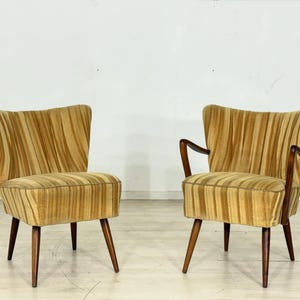 May include: Two vintage armchairs with a striped pattern in shades of gold and brown. The chairs have wooden legs and armrests. The backs of the chairs are curved, and the seats are cushioned.