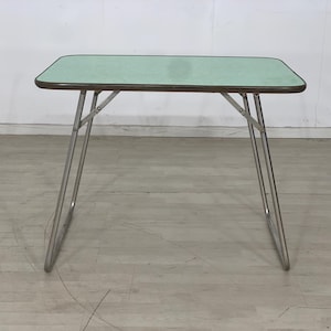 Può includere: Un tavolo pieghevole verde chiaro con un telaio in metallo argentato. Il tavolo è realizzato in un materiale leggero ed è perfetto per l'uso all'aperto.
