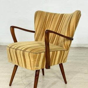 May include: A vintage armchair with a striped pattern in shades of gold and brown. The chair has a curved back, wooden armrests, and tapered legs. The upholstery features vertical stripes, and the wooden frame is a dark brown.
