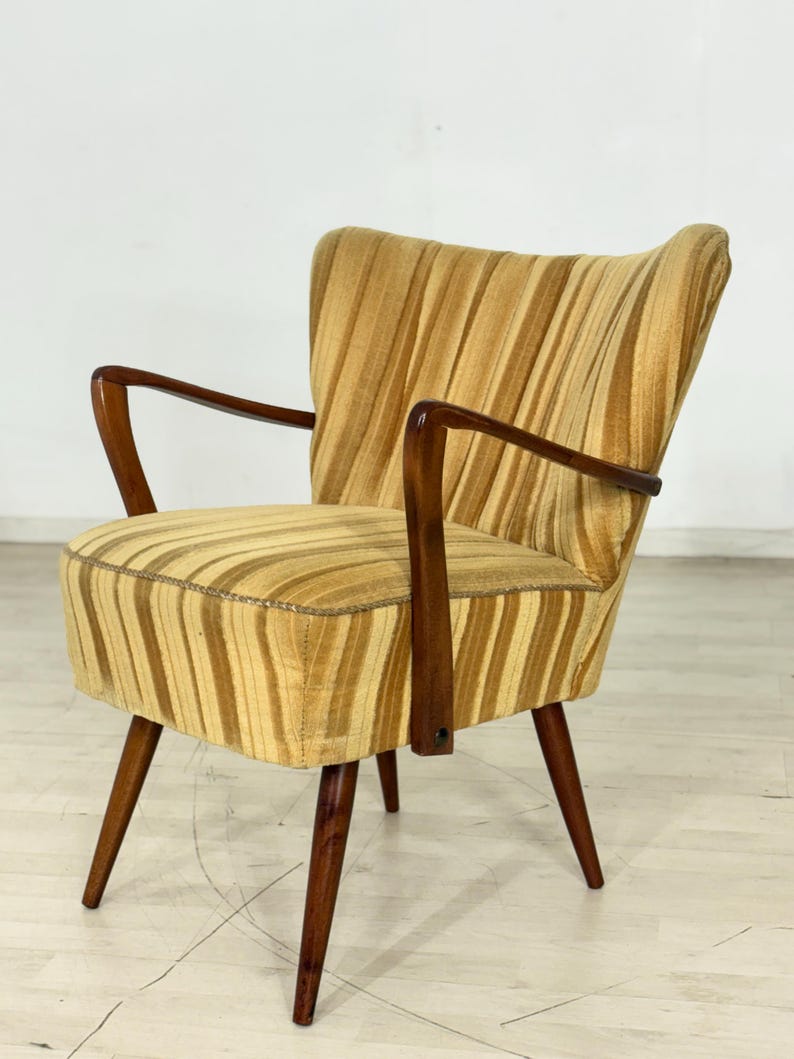 May include: A vintage armchair with a striped pattern in shades of gold and brown. The chair has a curved back, wooden armrests, and tapered legs. The upholstery features vertical stripes, and the wooden frame is a dark brown.