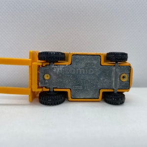 Pu&ograve; includere: Carrello elevatore a forche giocattolo giallo con ruote nere. La parte inferiore del camion ha il testo "Tomica 1/52 4  Komatsu Forklift Truck Made in Japan" stampato su di esso.