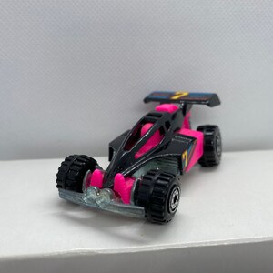 May include: A black and pink toy race car with a spoiler and the number "2" on the side.