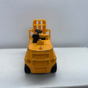 Pu&ograve; includere: Un carrello elevatore giocattolo giallo con un volante nero e un sollevatore nero.