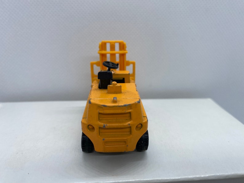 Pu&ograve; includere: Un carrello elevatore giocattolo giallo con un volante nero e un sollevatore nero.