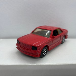 May include: A red toy car model of a Mercedes-Benz.