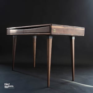 Peut inclure: Un bureau en bois foncé avec deux tiroirs et un plateau en noyer. Le bureau a quatre pieds avec des accents argentés. Le bureau est fabriqué par Diaz Marentes Studio.