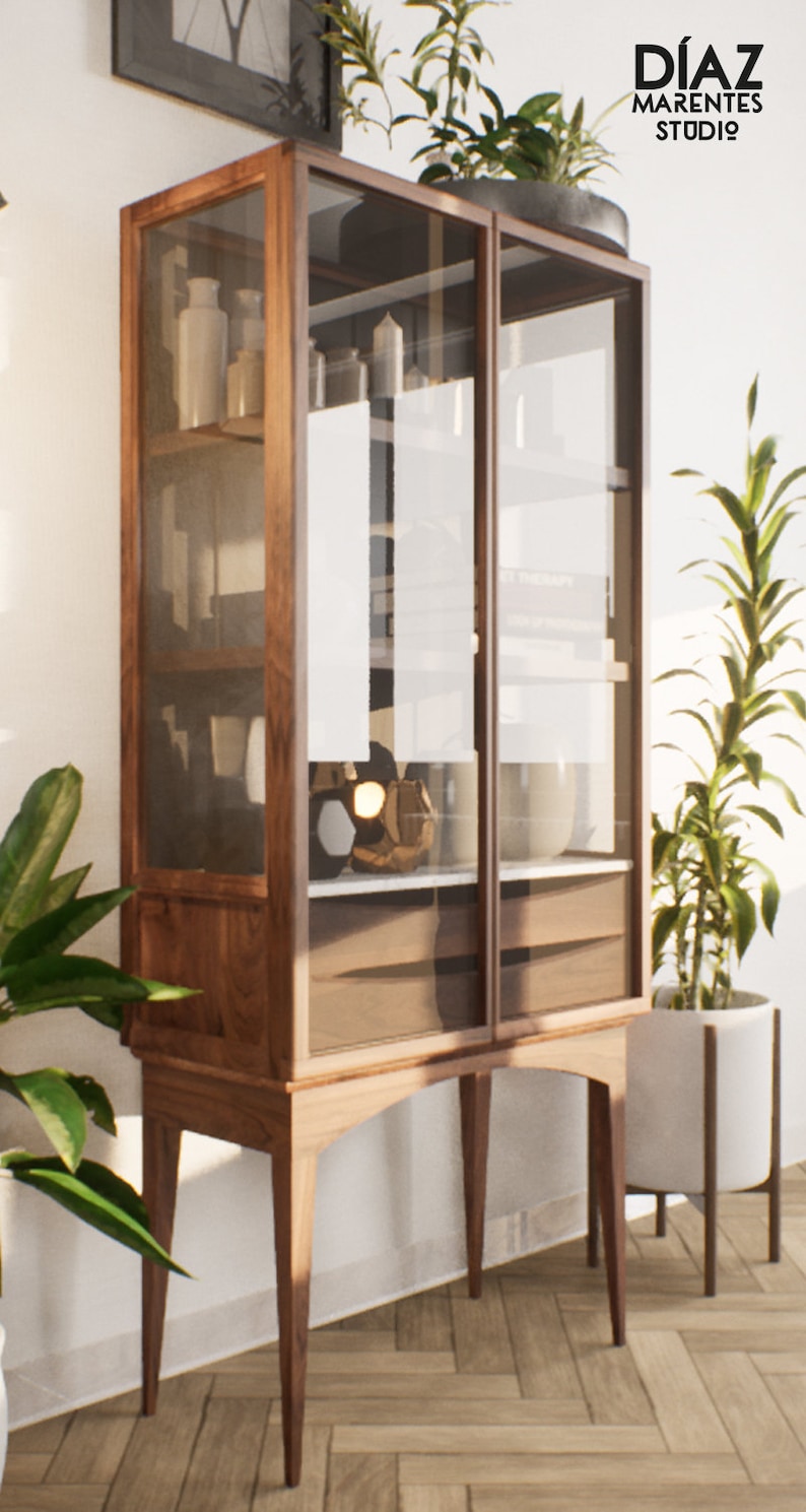 K&ouml;nnte beinhalten: Ein Schrank aus Holz mit Glast&uuml;ren und Regalen. Der Schrank steht auf vier Beinen und hat eine dunkelbraune Holzoptik. Der Schrank ist mit verschiedenen Gegenst&auml;nden gef&uuml;llt, darunter Vasen, B&uuml;cher und andere Dekorationsartikel.