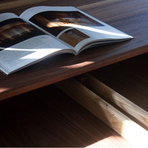 Puede incluir: Primer plano de un cajón de madera con dos cajones abiertos. Los cajones son de madera clara y tienen un acabado natural. Una revista está encima del cajón, cubriendo parcialmente el cajón superior.