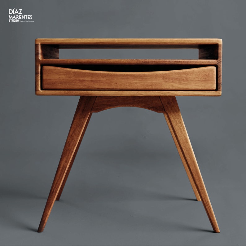 May include: A mid-century modern style wooden nightstand with a drawer and open shelf. The nightstand has angled legs and a warm brown finish. The design is minimalist and functional, suitable for a bedroom or living space.