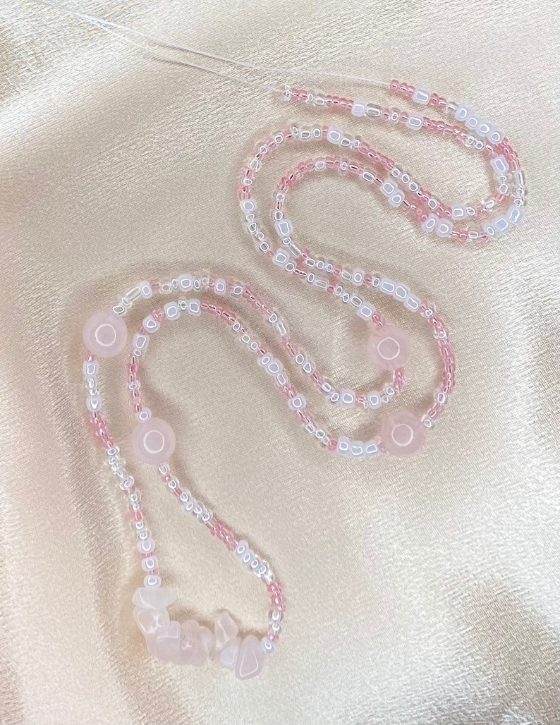 May include: A pink and white beaded necklace with rose quartz beads and a rose quartz charm.