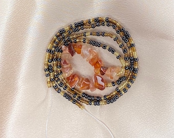 May include: A waist bead necklace with brown and gold beads and carnelian stones.