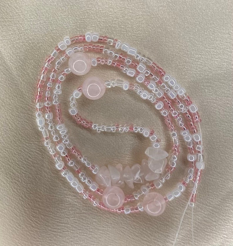May include: A pink and white beaded necklace with rose quartz beads and a few larger rose quartz stones.