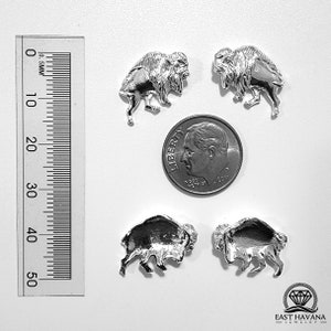 May include: Four silver buffalo charms, each approximately 1.5 cm in size, are displayed on a white surface next to a US dime for scale.
