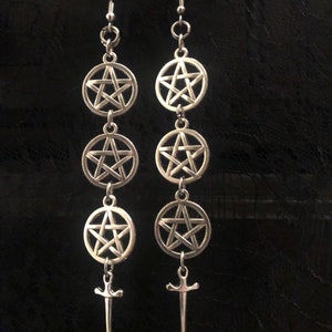 May include: A pair of silver earrings with a pentagram design. Each earring has three pentagram charms and a sword charm at the bottom.
