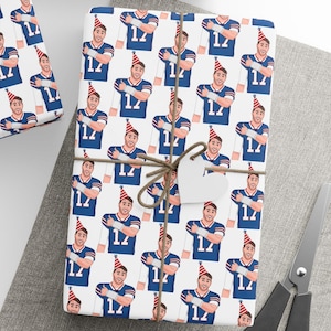 May include: Gift wrap featuring a repeating pattern of a person in a blue jersey with the number 12 and a party hat. The wrapped gifts are tied with twine and have blank tags. A ball of twine and scissors are also present.