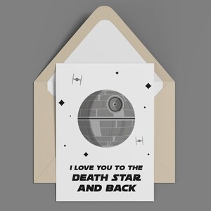 May include: A greeting card with a Death Star illustration and the text "I love you to the Death Star and back." The card is inside a tan envelope. The design includes TIE fighters and diamond shapes.