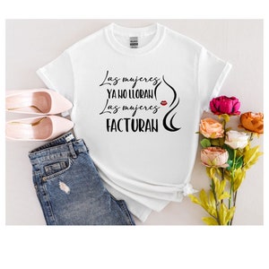 May include: White t-shirt with black text that reads "Las mujeres ya no lloran Las mujeres facturan" with a red lipstick graphic.