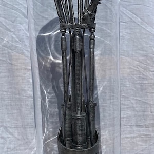 Puede incluir: Una mano robótica detallada de color plateado se muestra en un cilindro de vidrio transparente sobre una base negra. La mano está articulada y parece estar hecha de metal.