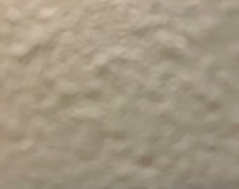 May include: A blurry image of a textured, off-white surface. The surface appears to have a slightly uneven texture with small, rounded bumps and a subtle gradient of light and shadow.