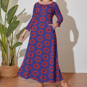 May include: A long-sleeved maxi dress with a blue background and a red donut pattern. The dress has a round neckline and a single pocket on the left side.