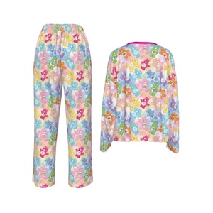 K&ouml;nnte beinhalten: Ein zweiteiliges Pyjama-Set mit einem sich wiederholenden Muster von Care Bears in verschiedenen Farben. Das Set beinhaltet ein lang&auml;rmliges Oberteil mit pinkfarbenem Kragen und eine passende Pyjamahose. Die Pyjamas sind wei&szlig;.