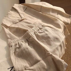 Pu&ograve; includere: Un pigiama in lino beige con camicia a collo e pantaloncini. La camicia ha una chiusura con bottoni e i pantaloncini hanno una cintura elastica.