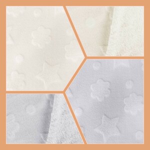 May include: Close-up of four white fabric swatches with different embossed patterns. The patterns include stars and flowers.