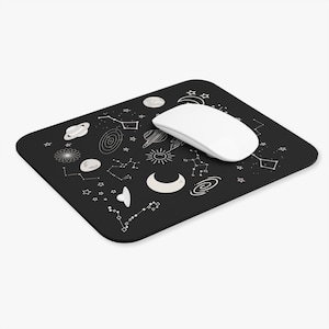 May include: A black mouse pad with a white design of planets, stars, and constellations. A white computer mouse is on top of the mouse pad.