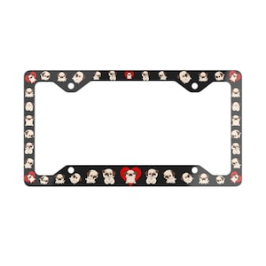 May include: A black rectangular license plate frame featuring a repeating pattern of cartoon pug dogs in various poses, interspersed with small red heart icons. The frame has four circular mounting holes positioned at the corners.