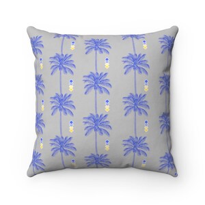May include: A gray throw pillow with a repeating pattern of blue palm trees and yellow and blue geometric shapes.