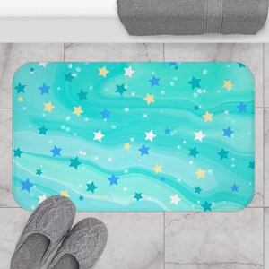 May include: A turquoise blue bath mat with a white, yellow, and blue star pattern. The mat has a wavy, marbled design.