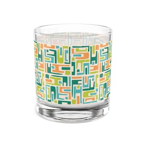 May include: A clear glass tumbler with a geometric pattern in shades of green, orange, and blue. The pattern is reminiscent of mid-century modern design.