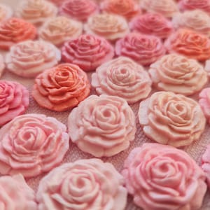Könnte beinhalten: Eine Sammlung von Zuckerrosen in Rosa und Pfirsich, perfekt zum Dekorieren von Kuchen und Cupcakes.