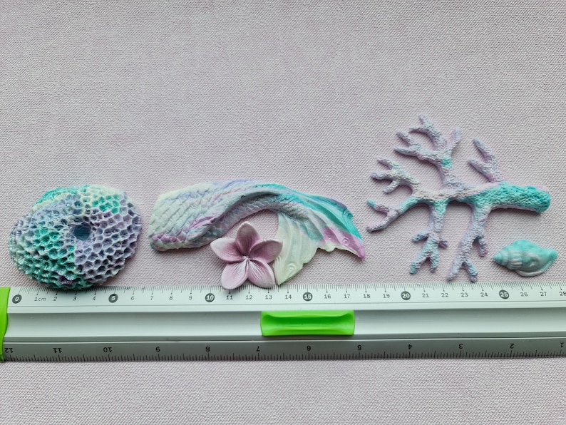 May include: A set of five pastel-colored resin sea life ornaments. The set includes a mermaid tail, a coral branch, a seashell, a flower, and a coral reef. The ornaments are approximately 2-3 inches in size.