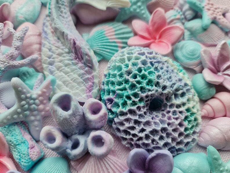 May include: A collection of pastel-colored, handmade, polymer clay sea-themed decorations. The decorations include starfish, seashells, coral, and flowers.