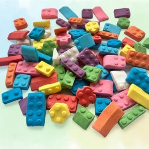 Puede incluir: Una colección de bloques de construcción de juguete coloridos en varias formas y tamaños. Los bloques son en tonos de rojo, naranja, amarillo, verde, azul, rosa, morado y blanco. La imagen muestra una variedad de diseños de bloques.