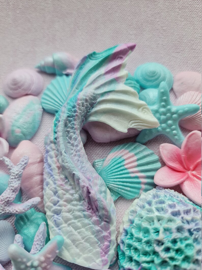 May include: A mermaid tail made of pastel blue, purple, and white resin with a shimmery finish. The tail is surrounded by various sea-themed decorations, including seashells, starfish, and coral.