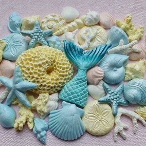 May include: A collection of blue and yellow seashell-shaped cake decorations, including a mermaid tail, starfish, and coral.